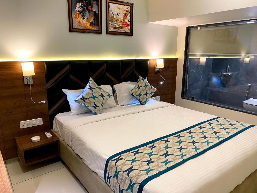 a bedroom with a large bed with a large window at Townhouse Vadodara Railway Junction Formerly Hotel Unique in Vadodara