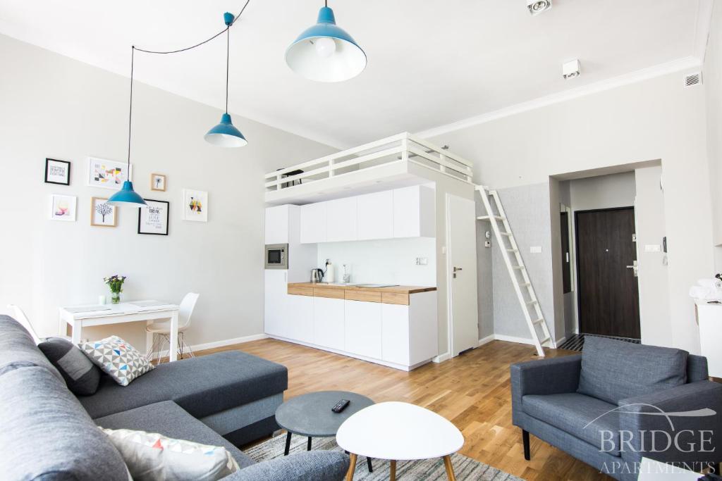 a living room with blue couches and a kitchen at Bridge Apartments in Krakow