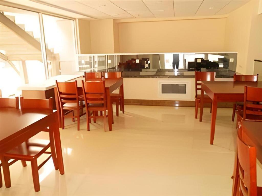 eine Küche und ein Esszimmer mit Holztischen und Stühlen in der Unterkunft GreenTree Inn Weihai Liugongdao Wharf Qingdao North Road Express Hotel in Weihai