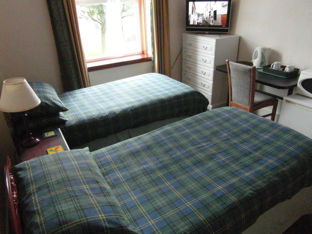 a bedroom with two beds and a desk and a dresser at Abacus Central Guest House in Aberdeen