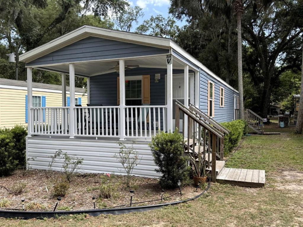 ein kleines blaues Haus mit einer Veranda und einer Terrasse in der Unterkunft Modern Cottage with Incredible Amenities and Rainbow River Access near Dunnellon, Florida in Dunnellon