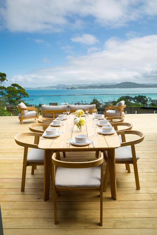 a long wooden table with chairs on a deck at Seaviews and a stroll to Whanagaumu bay in Whangarei