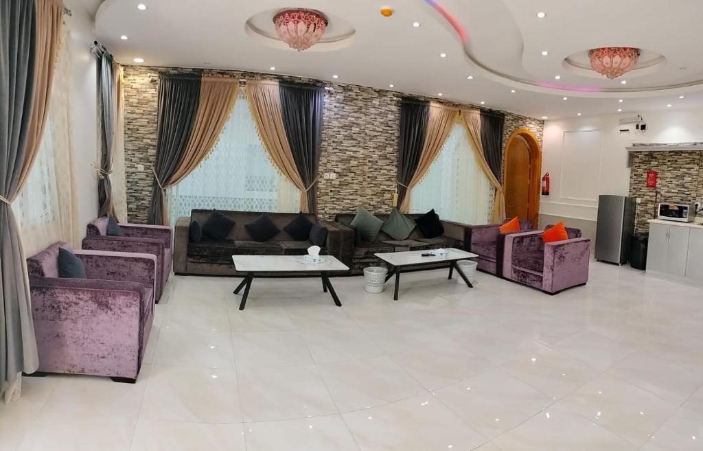 ein Wohnzimmer mit lila Sofas, Tischen und Fenstern in der Unterkunft منتجع الكناري in Ta'if