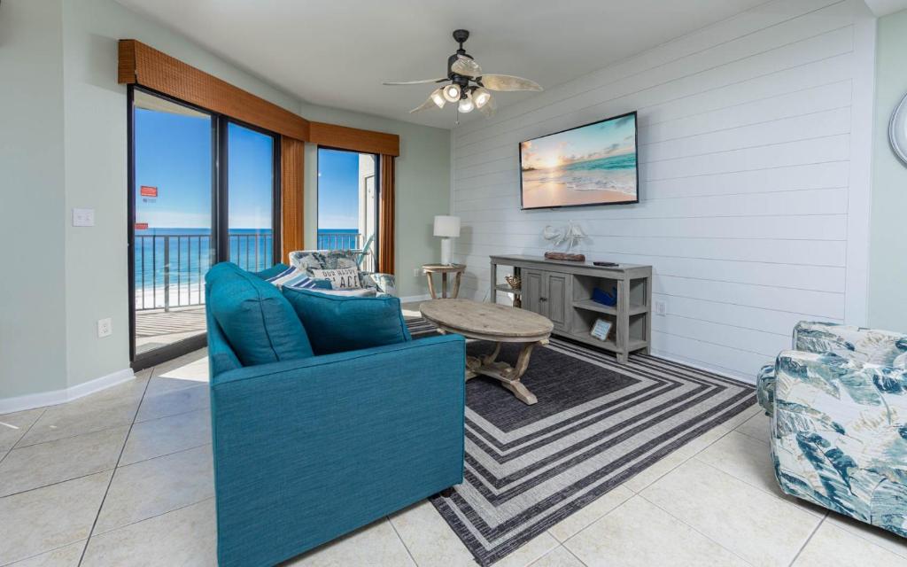 a living room with a blue couch and a table at Phoenix VI 61115 in Orange Beach