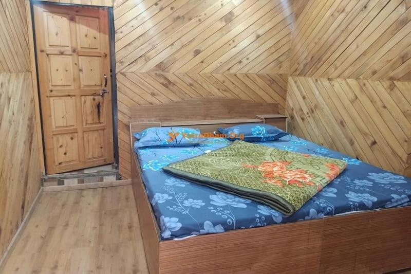 a bed in a wooden cabin with a blanket on it at Hotel Priyanshu in Madheso