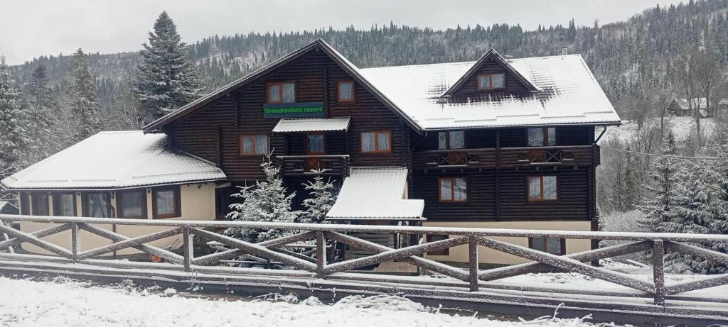 a log cabin with snow on the roof at Drozdovichi Resort in Oryavchyk