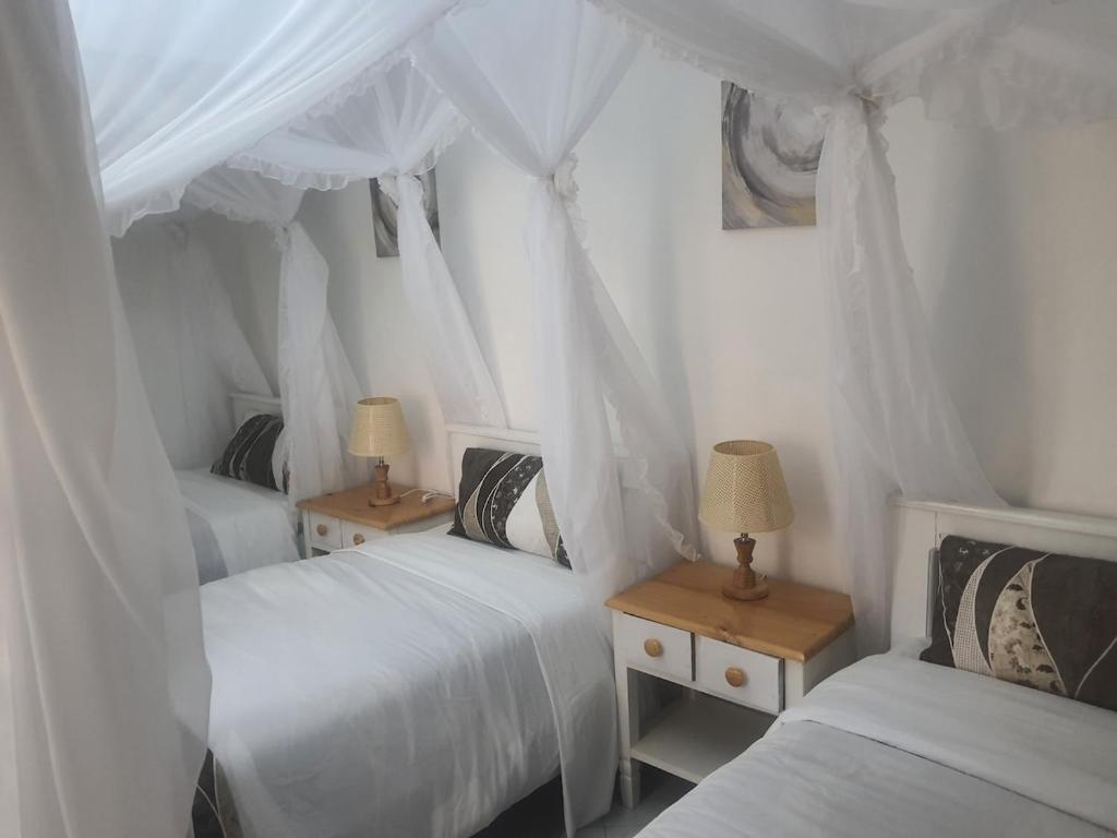 ein Schlafzimmer mit zwei Betten und zwei Tischen mit Lampen in der Unterkunft 41 Nile Bridge Villa in Jinja