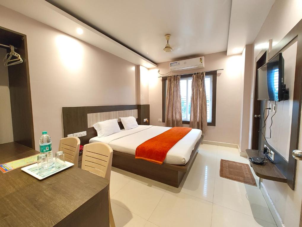 Un dormitorio con una cama, una mesa y un televisor. en Hotel HTN Stay Puri Near Golden Beach and Temple - Air-Conditioned With Lift #wi-fi And Parking Facilities - Spacious Room - Prime Location Book It Early, en Puri