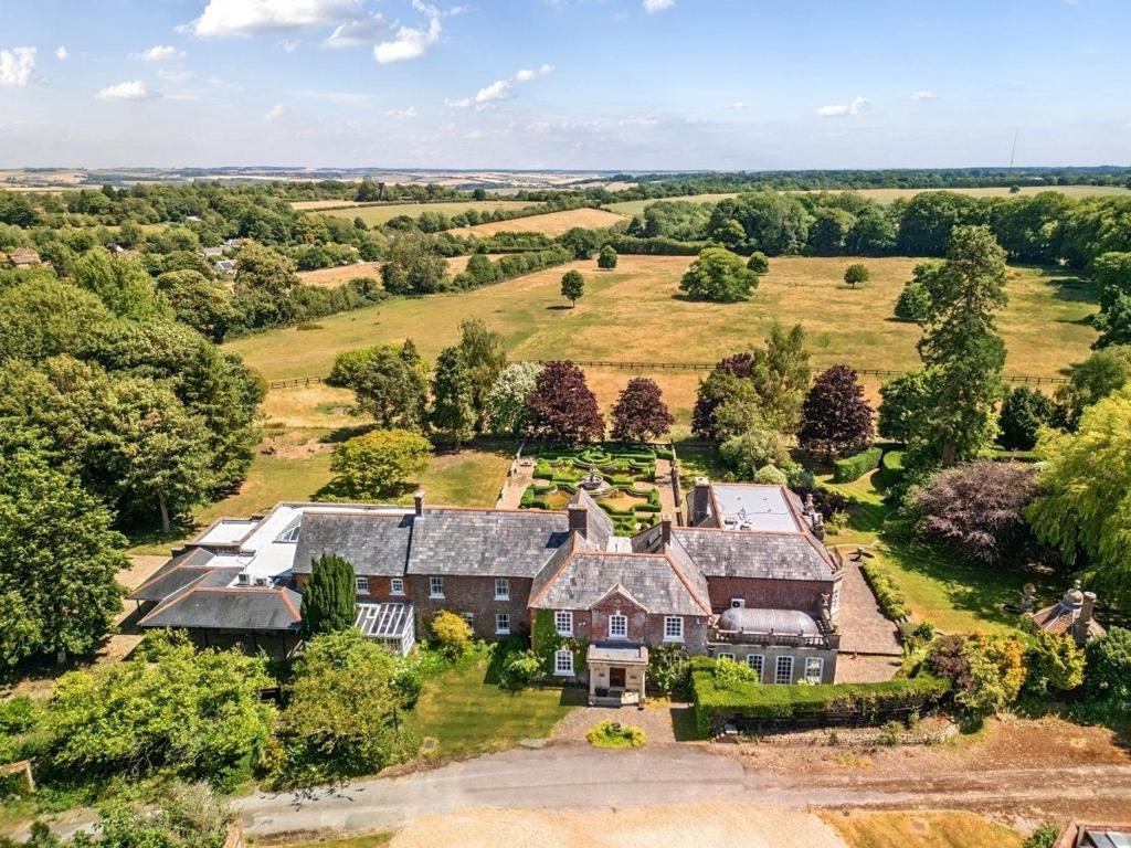 eine Luftaufnahme eines großen Hauses auf einem Feld in der Unterkunft The Baydon House Luxury Studio in Aldbourne