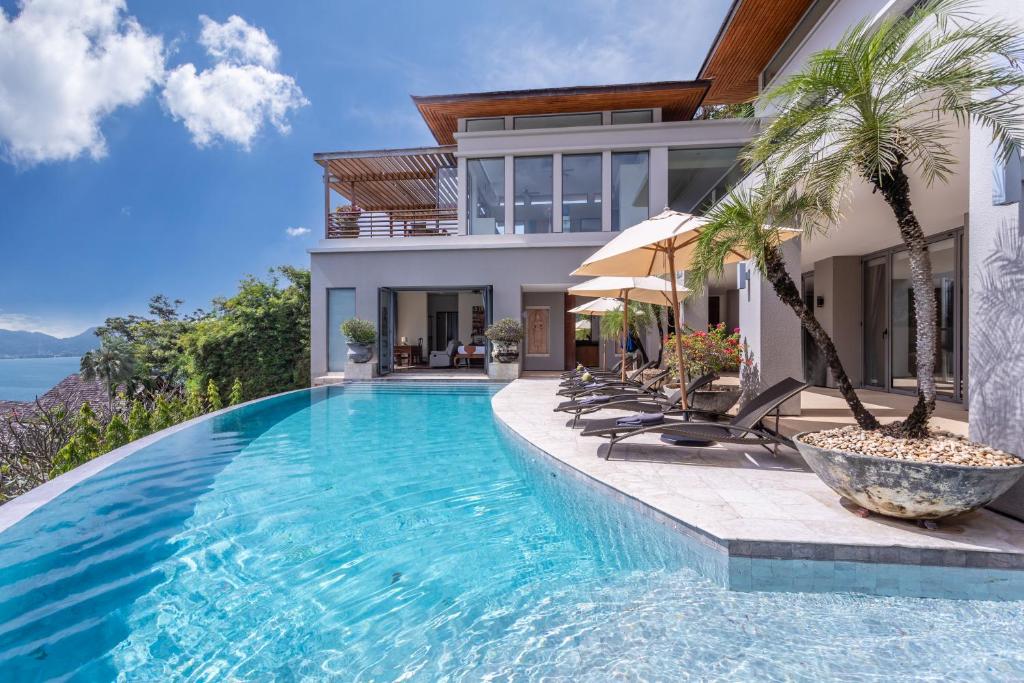 a villa with a swimming pool in front of a house at Villa Fah Sai in Phuket