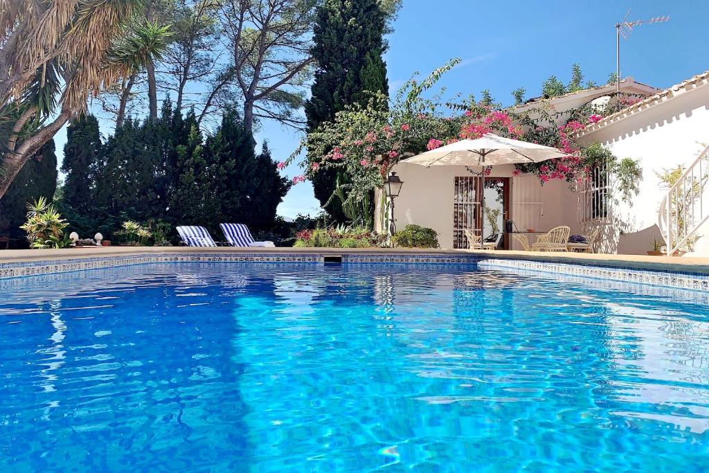 a swimming pool with two chairs and an umbrella at La Cortijera in Benidoleig