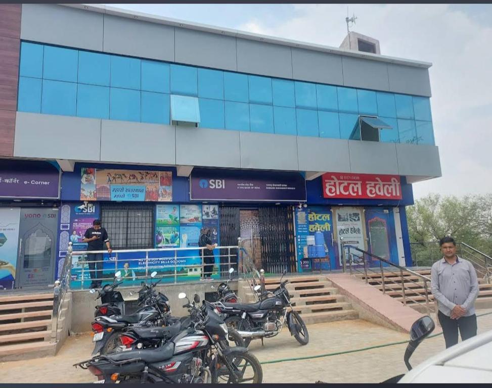 un homme debout devant un bâtiment équipé de motocycles dans l'établissement Hotel haveli, à Rāmgarh