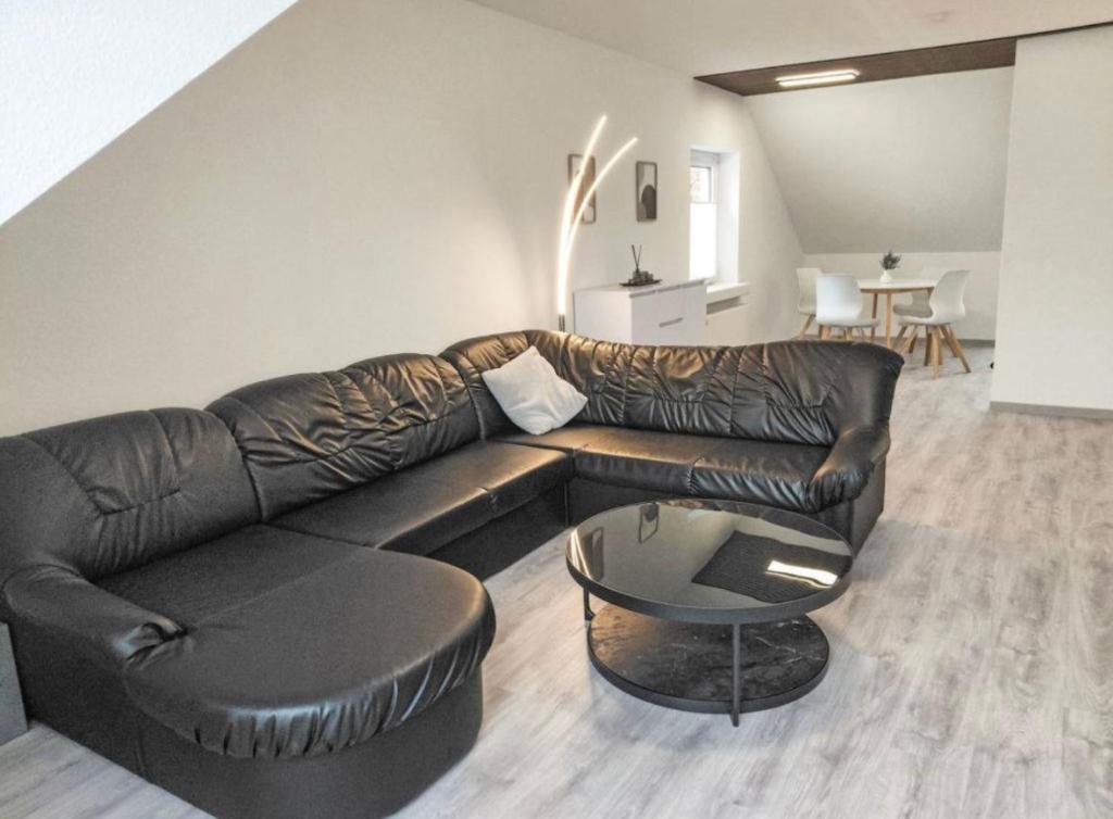 ein Wohnzimmer mit einer Ledercouch und einem Tisch in der Unterkunft Ferienwohnung Sonnenschein in Bad Pyrmont