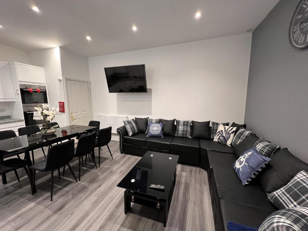 a living room with a black couch and a table at Higher Lane House in Plymouth