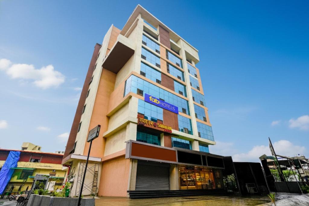 a tall building with a blue sign on it at FabHotel Sarah Inn - Nr Kasheli Metro Station in Bhiwandi