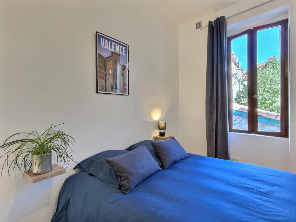 a bedroom with a blue bed and a window at La Cachette in Valence