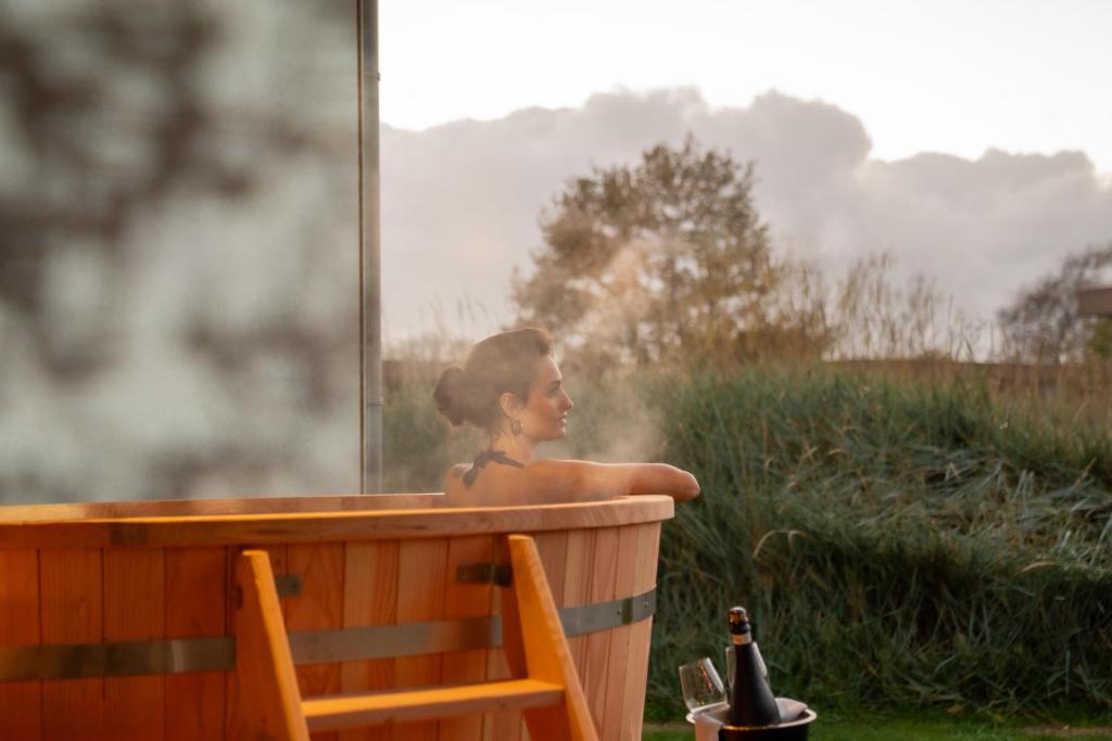 uma menina sentada em uma banheira em uma janela em Garden Suites with private hot tub em Burgh Haamstede