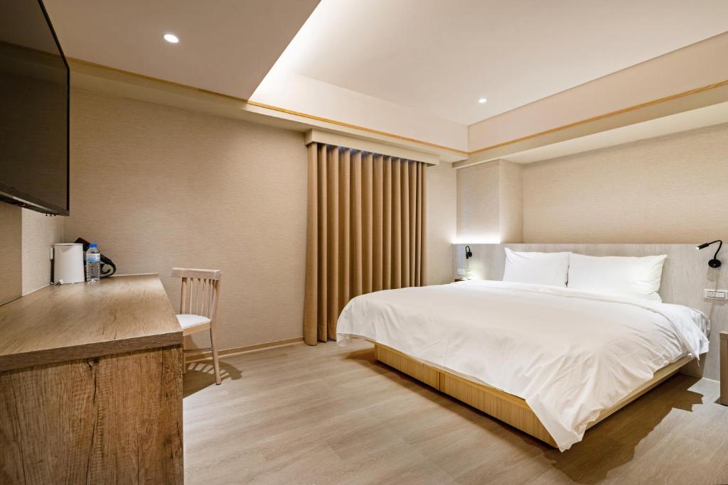 una habitación de hotel con una cama y un televisor en 衿后禾居Good Hotel, en Kaohsiung
