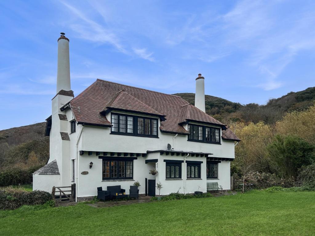 a white house with two chimneys on top of a field at Bossington Green Cottage in Porlock