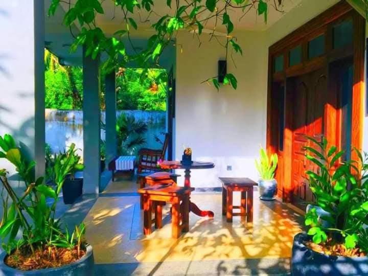 a living room with a table and chairs and plants at Baba Place Thalpe in Galle