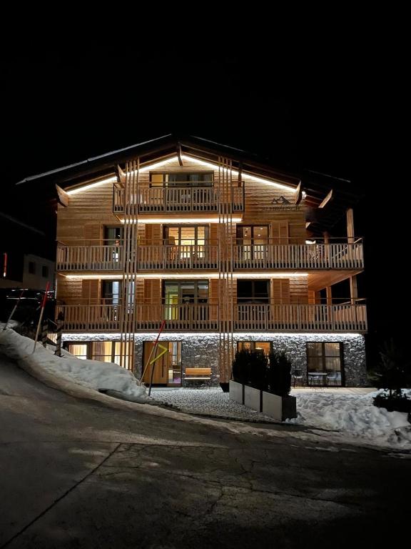 a large wooden building at night with snow around it at Almrausch Lech Apartments in Lech am Arlberg