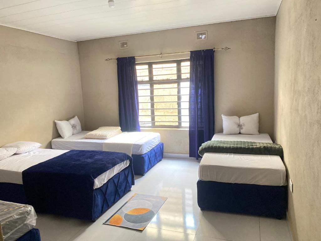 a room with three beds and a window at Executive house in Lusaka