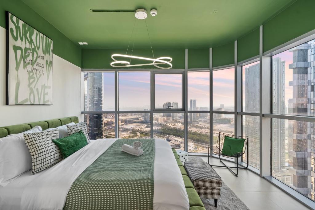 a bedroom with a large bed with green walls and windows at Luxury Radiant Boulevard Residence in Mushayrib