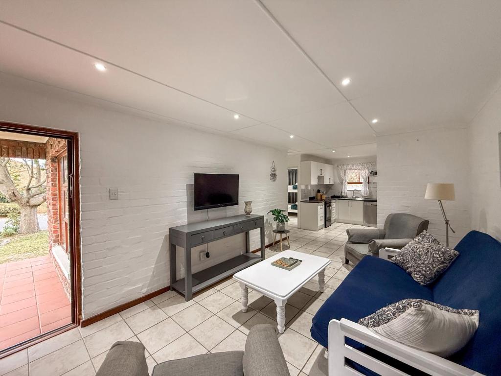 Gulls Nest في هيرمانوس: غرفة معيشة مع أريكة زرقاء وتلفزيون