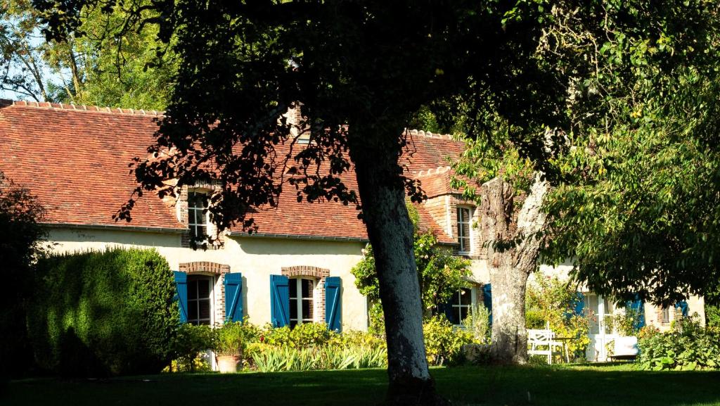 une maison blanche avec un toit rouge et un arbre dans l'établissement Chambre d'Hôtes La Ferme du Pré-Martin, à La Génevraie