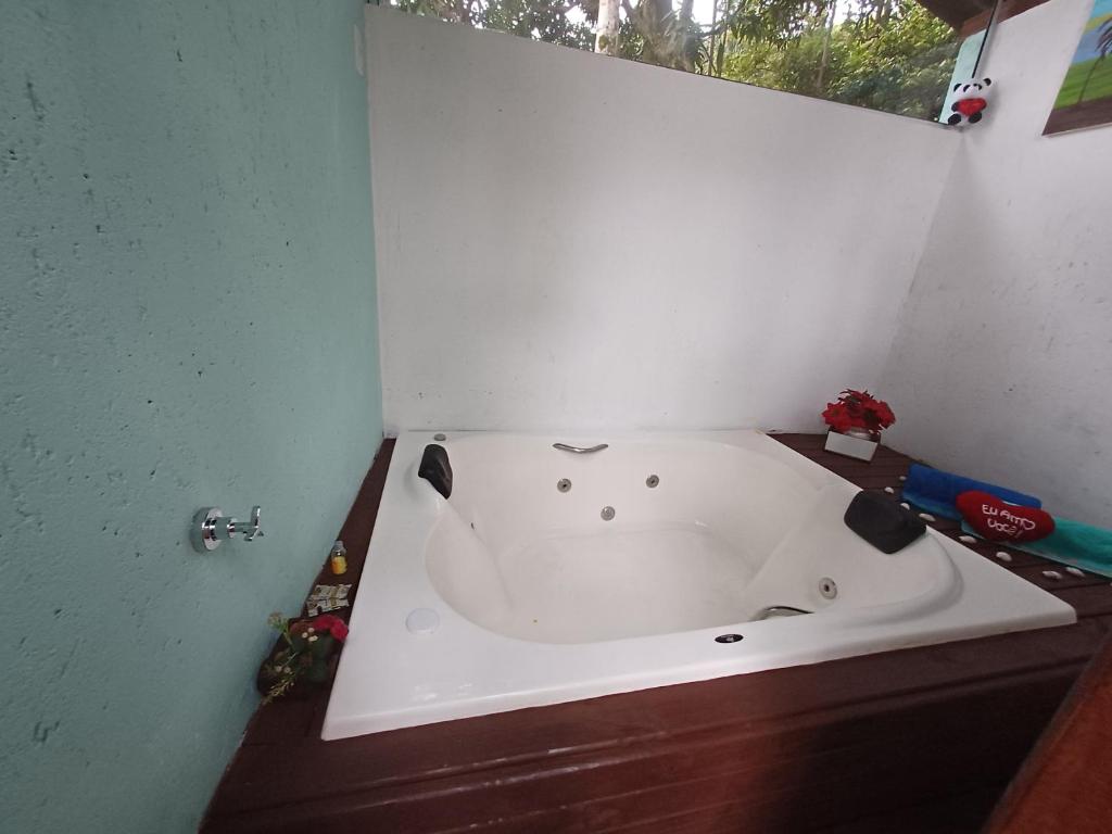 a white bath tub in a bathroom with a window at Chalé com jacuzzi Florianópolis in Florianópolis