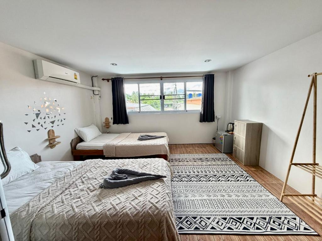 ein Schlafzimmer mit zwei Betten und einem Fenster in der Unterkunft TIDE & TRIBE HOSTEL Phangan in Thongsala