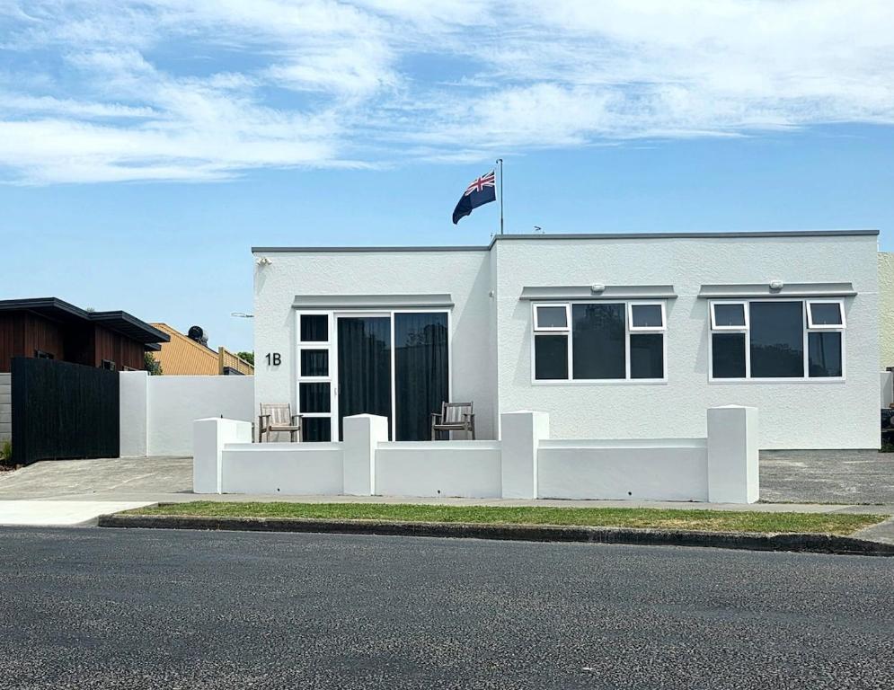 Ein weißes Haus mit einer Flagge darüber in der Unterkunft Deco Nook Napier Iconic Art Deco Hideaway in Napier