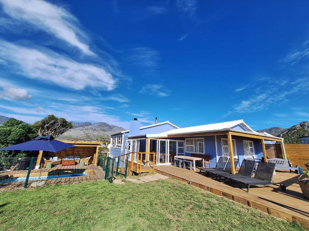 a blue house with a deck and an umbrella at The Mermaid's Tail in Pringle Bay