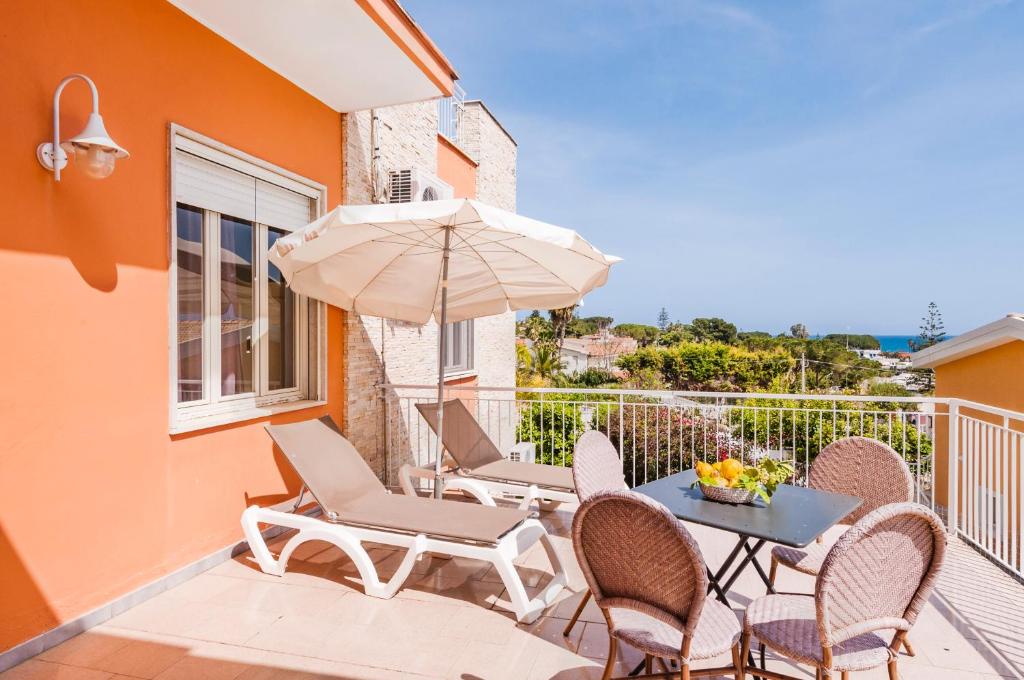a patio with a table and chairs and an umbrella at Stella del mare Apartments in Fontane Bianche