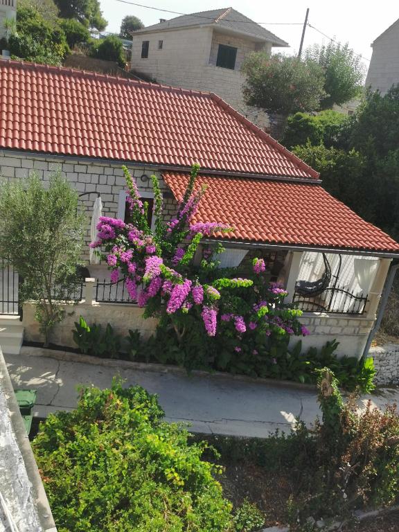 a house with purple flowers on the side of it at apartman house Bjedov in Povlja