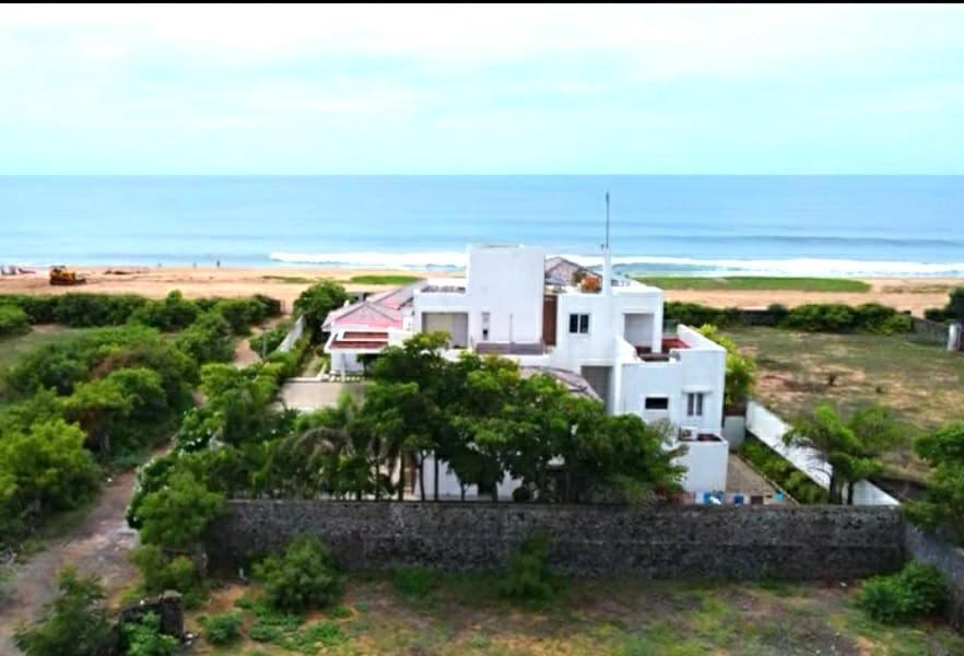 a white house with the ocean in the background at Manoj hotel in in Covelong