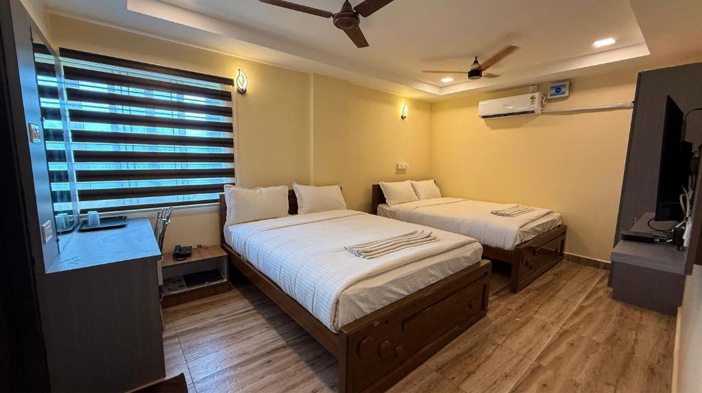 a room with two beds and a television in it at Lakshmi Narayana Grand in Kanchipuram