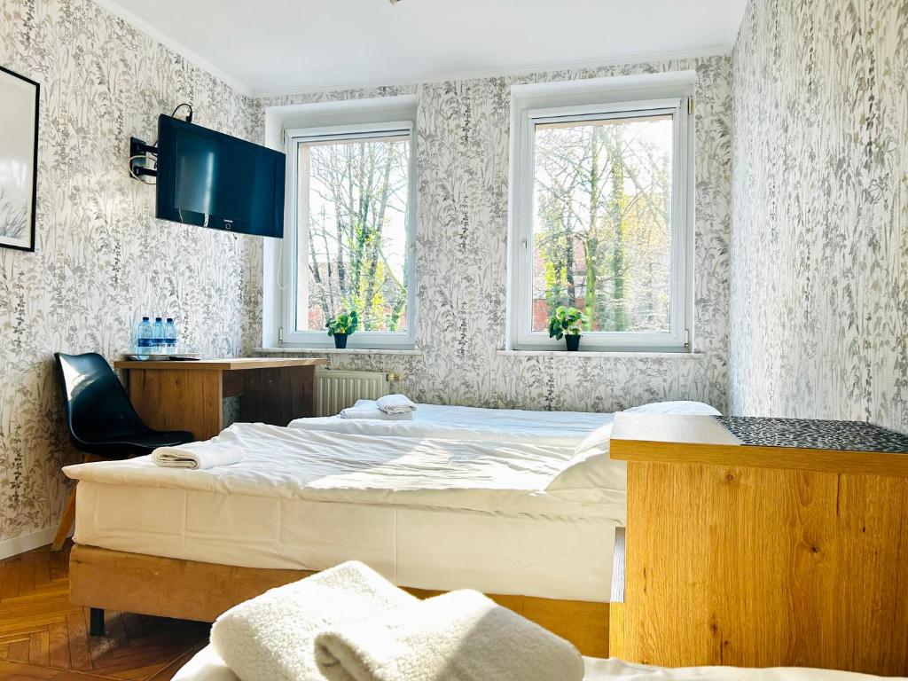 ein Schlafzimmer mit einem großen Bett und zwei Fenstern in der Unterkunft Stary Młyn in Żory