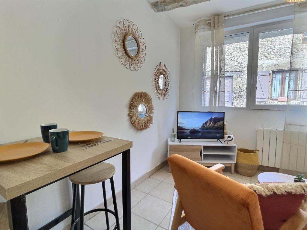 un salon avec une table et une télévision dans l'établissement Le Vercors, à Chabeuil