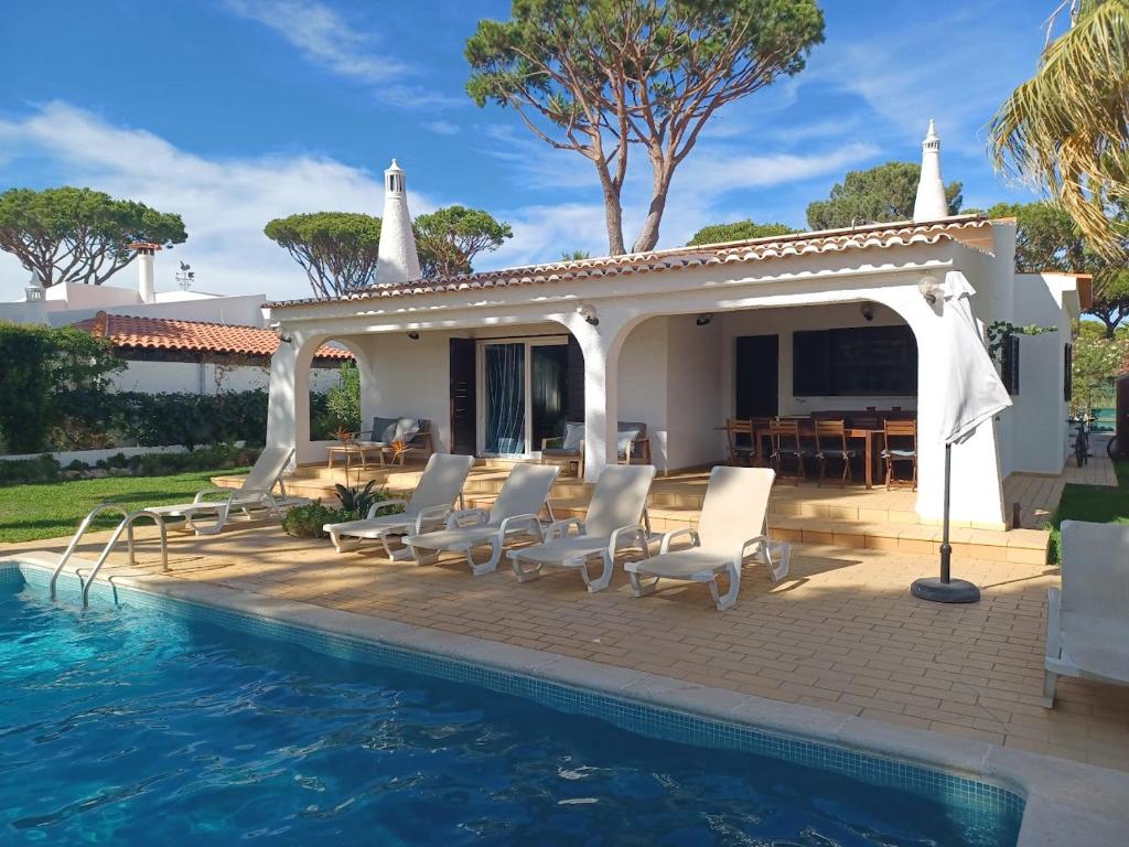a villa with a pool and chairs and a house at Alsouk in Vilamoura