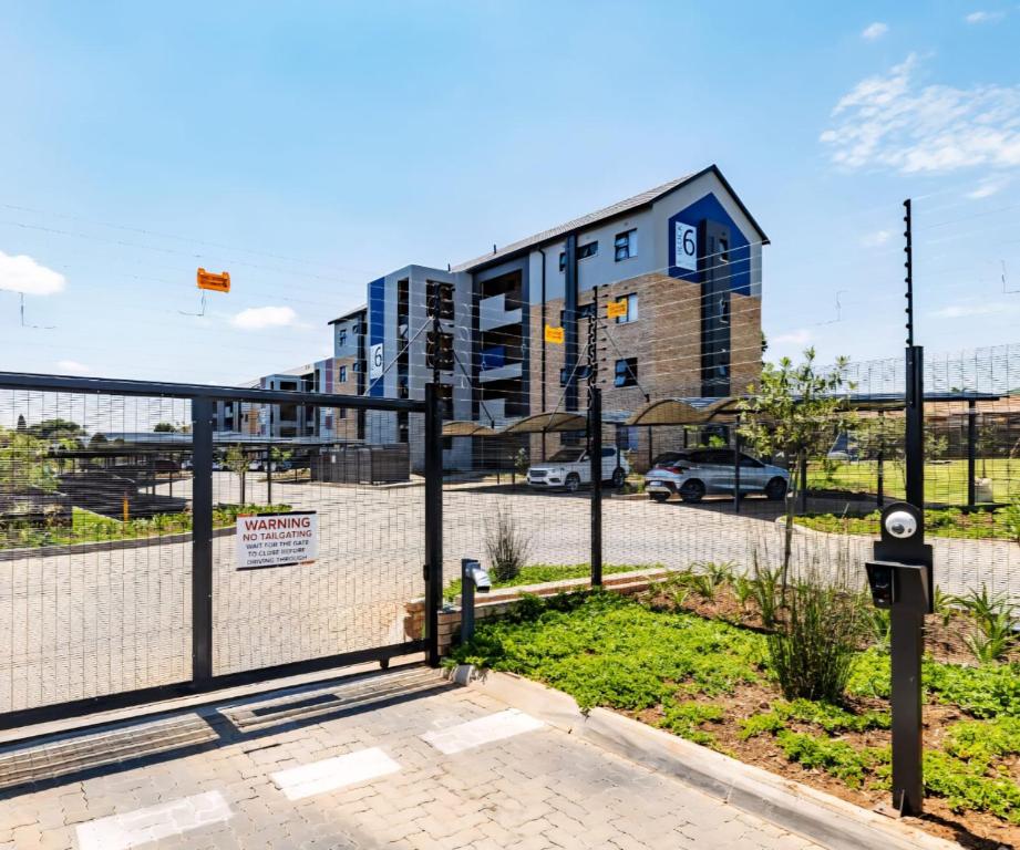 ein Zaun vor einem Gebäude mit einem Parkplatz in der Unterkunft Felinga Guest House in Centurion