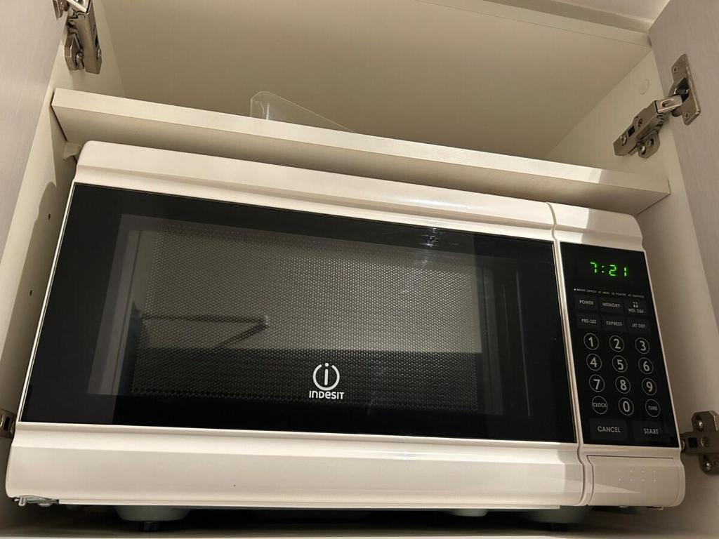 a microwave oven in a kitchen with the clock on it at Auckland CBD Apartment with Sky Tower View in Auckland