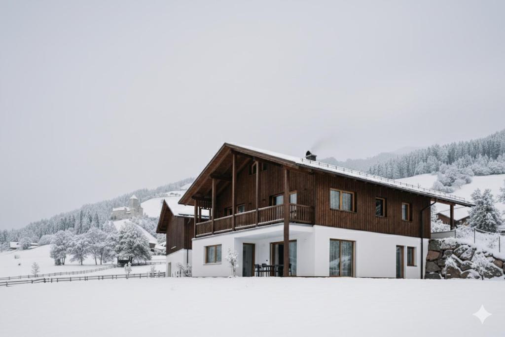Una casa con nieve en el suelo delante de ella. en Baumannhof, en Sarentino