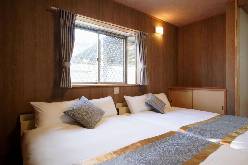 zwei Betten in einem kleinen Zimmer mit Fenster in der Unterkunft 糸島リトリートヴィラ芥屋 in Itoshima