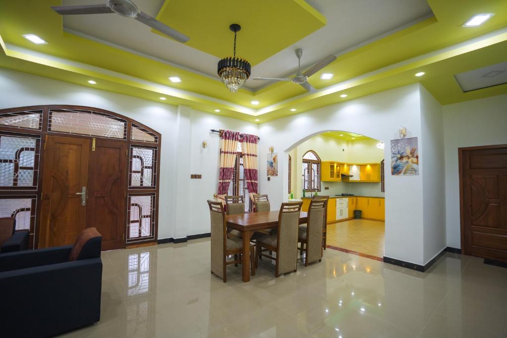 a dining room and living room with a table and chairs at Palm Villas Jaffna in Jaffna