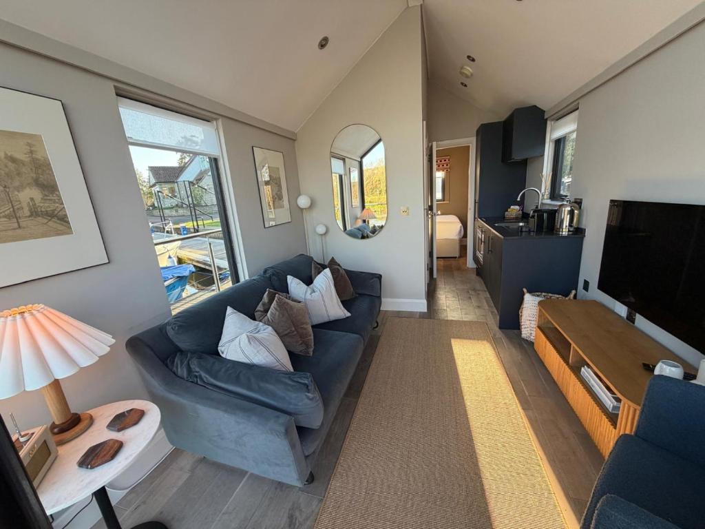 ein Wohnzimmer mit einem blauen Sofa und einem Fernseher in der Unterkunft Water Cabin With Water Sports Equipment and Bikes, Bath in Bristol
