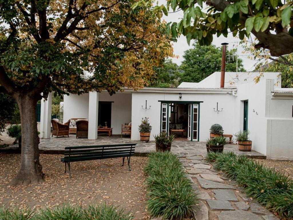 a bench sitting in front of a white house at Karoo Cypress Guesthouse in Graaff-Reinet