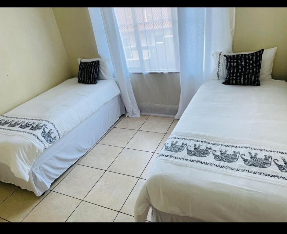 two beds in a small room with a window at Franjipani in Margate