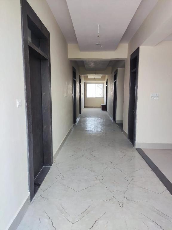 an empty hallway with black doors and a tile floor at Shubham guest house in Gwalior
