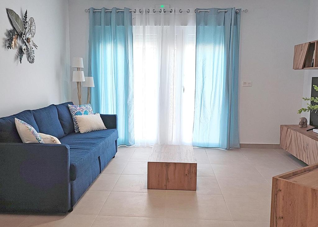 a living room with a blue couch and blue curtains at Ría Vale 2 in Santa Marta de Magasca
